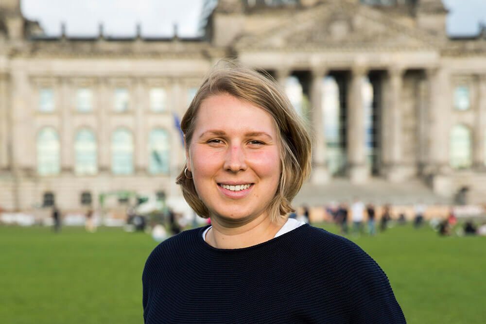 Porträtaufnahme von Denise Loop vor dem Bundestagsgebäude
