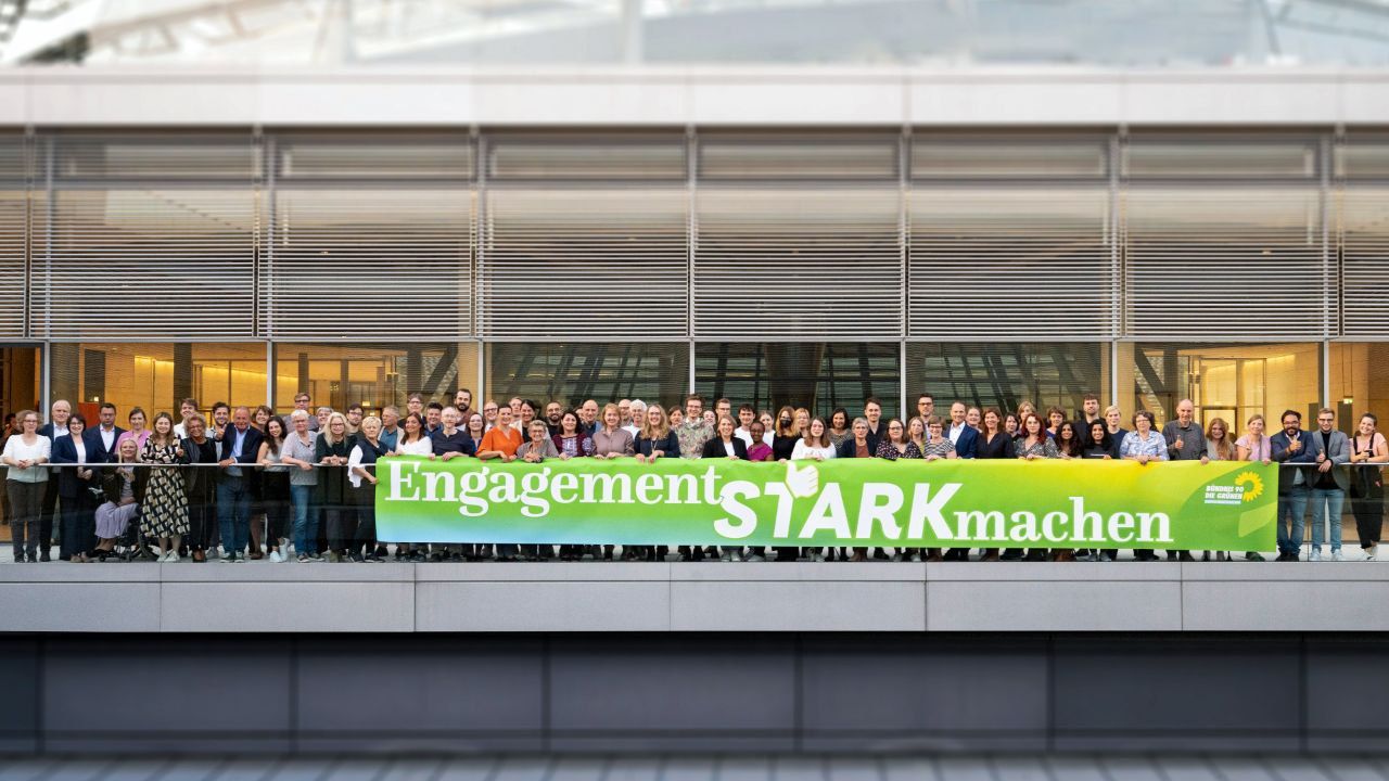 Auf dem Foto sieht man eine Gruppe von Menschen hinter einem Grünen Plakat mit der Aufschrift "Engaggement Stark machen"
