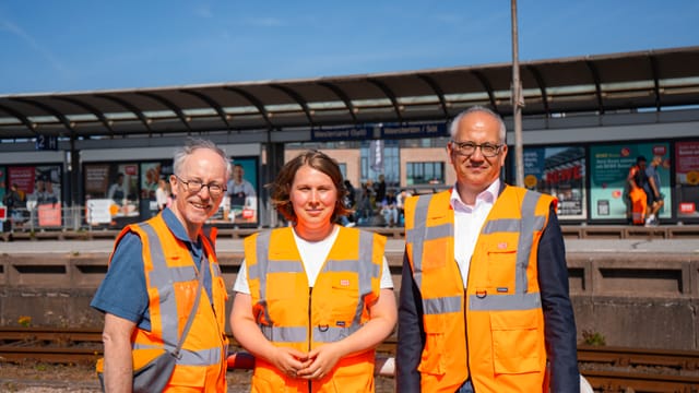 Matthias Gastel (links), Denise Loop (Mitte) und Tarek Al-Wazir (rechts) stehen am Bahnhof in Westerland (Sylt).
